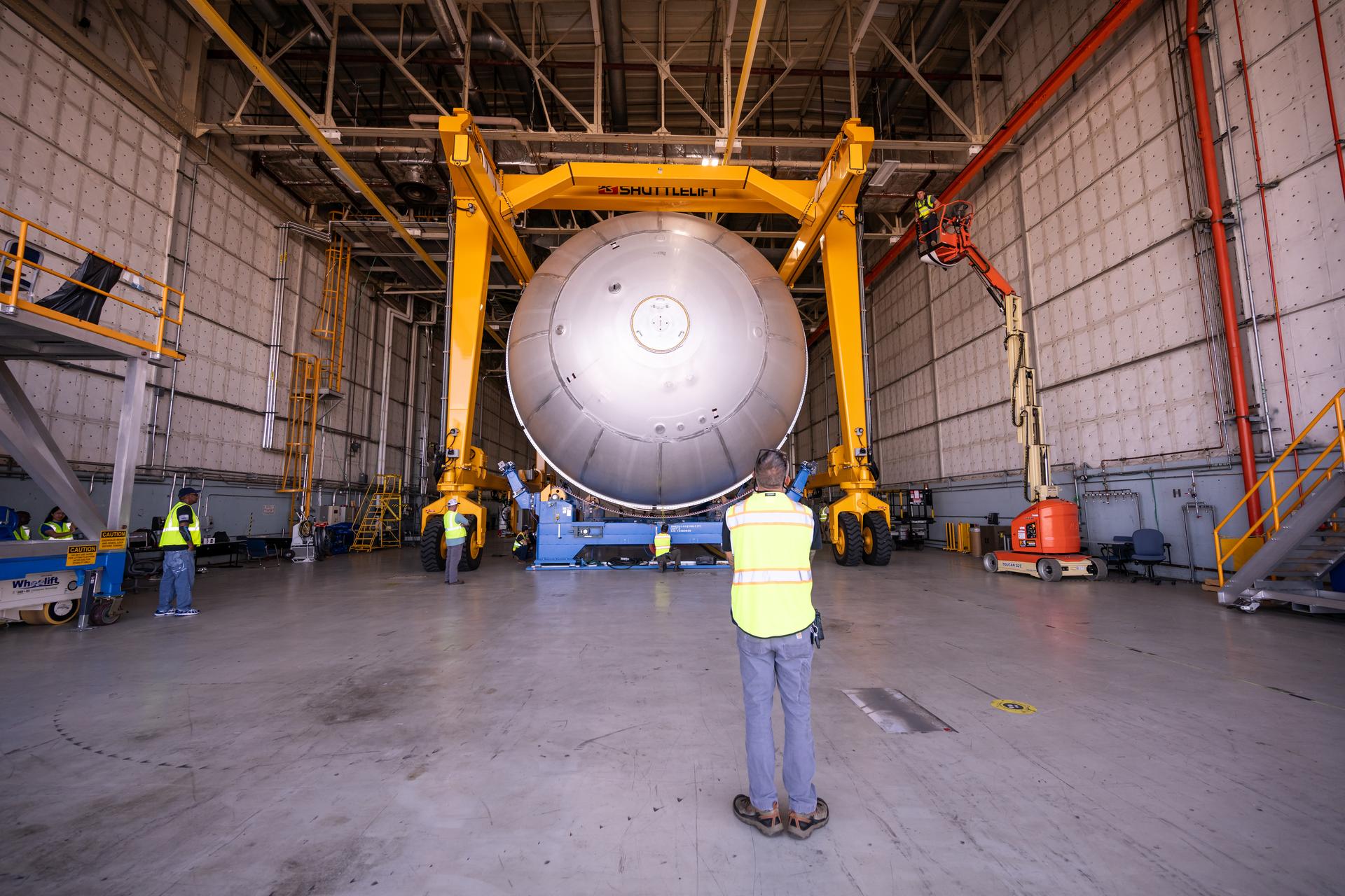 Teams at NASA’s Michoud Assembly Facility in New Orleans move a liquid oxygen tank from the main rocket factory into the adjacent vertical assembly building. The liquid oxygen tank, which will form part of the SLS (Space Launch System) rocket for NASA’s Artemis IV mission to the Moon, is rotated from a horizontal to a vertical configuration and loaded into the high bay’s hydrostatic proof testing cell. This non-destructive evaluation method tests the structural integrity of the tank’s welds by filling the tank with water, simulating the propellant used during launch. The propellant tank will hold more than 196,000 gallons of super-cooled liquid oxygen at launch and is one of five major elements that make up the 212-foot-tall SLS rocket stage. The core stage, along with its four RS-25 engines at its base, produces more than two million pounds of thrust to help launch NASA’s Orion spacecraft, astronauts, and supplies beyond Earth’s orbit and to the lunar surface for Artemis.